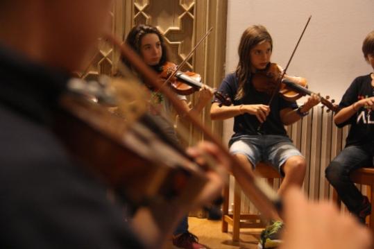 Pla detall d'un nen tocant el violí amb tres instrumentistes més darrera, a l'escola de música de Can Ponsic, a Sarrià. ACN