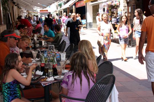 El carrer dos de maig de Sitges ple de turistes que passegen i mengen a la terrassa d'un restaurant. ACN