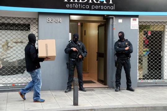 Imatge de dos mossos a la porta in un tercer entrant amb una caixa al número 84 del carrer Dolors Almeda de Cornellà de Llobregat. ACN