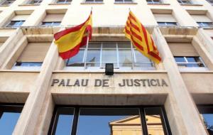 Pla contrapicat de la façana d'entrada a l'Audiència de Tarragona, amb el rètol de 'Palau de Justícia' i les banderes espanyola i catalana. Imatge del