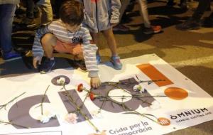 Un nen dipositant un clavell al damunt de la pancarta amb el lema 'Democràcia', aquest 20 de setembre. ACN / Xavier Pi