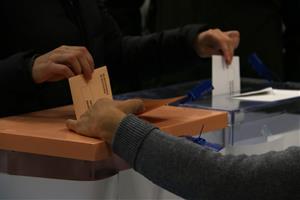 Pla detall d'una mà dipositant les paperetes de les eleccions al Congrés dels diputats i al Senat en una urna. ACN