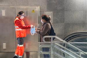 Pla obert d'una voluntària de la Creu Roja entregant una mascareta a l'estació de metro Diagonal de Barcelona. ACN