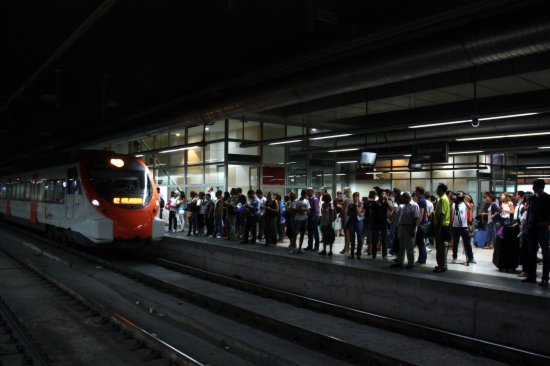 Diversos passatgers esperen un tren a l'estació de Sants  