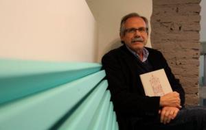 Antoni Dalmau assegut en un banc sostenint un exemplar del seu nou llibre durant l'entrevista. ACN
