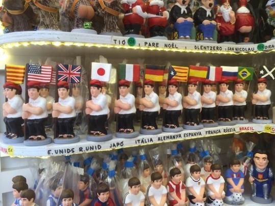 Diversos caganers amb banderes internacionals en una prestatgeria. ACN