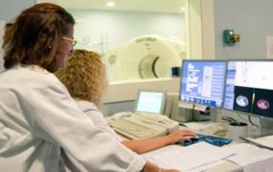 Dues doctores, d'esquena, utilitzen l'equipament necessari per realitzar una nova prova diagnòstica de la malaltia d'Alzheimer. ACN