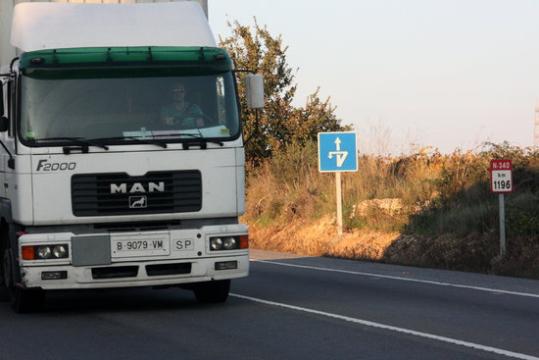 En primer pla, un camió que circula per l'N-340 a l'altura de Bellvei, amb un indicador quilomètric al fons. ACN