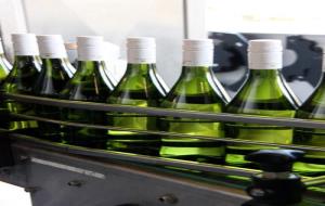 Imatge de diverses ampolles de vi blanc en procés d'embotellament i etiquetatge