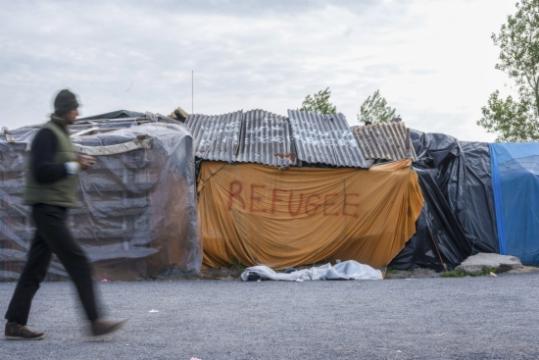 Un home camina per davant d'una tenda d'un espai per a refugiats a Calais, a França. ACN