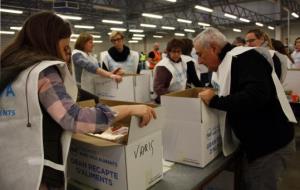 Activitat en una de les tres cintes de la nau de la Zona Franca on els classifiquen els aliments recollits en el Gran Recapte. ACN