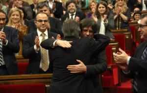 Artur Mas abraça Carles Puigdemont entre aplaudiments dels diputats de Junts pel Sí a l'inici del debat d'investidura. ACN