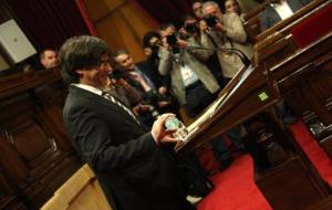 El candidat a la presidència de la Generalitat, Carles Puigdemont, somriu mentre s'omple el got d'aigua abans de començar el seu discurs d'investidura
