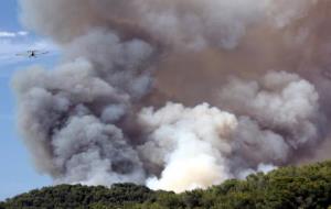 Espessa columna de fum de l'incendi de la Pobla de Montornès. Pla general de la fumera amb un hidroavió sobrevolant la zona. ACN