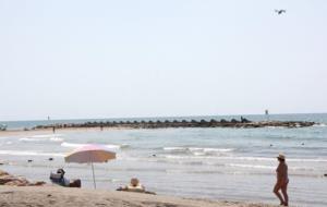 Gran pla general d'una platja de Cunit, amb banyistes passejant i prenent el sol, mentre el dron sobrevola la zona. ACN
