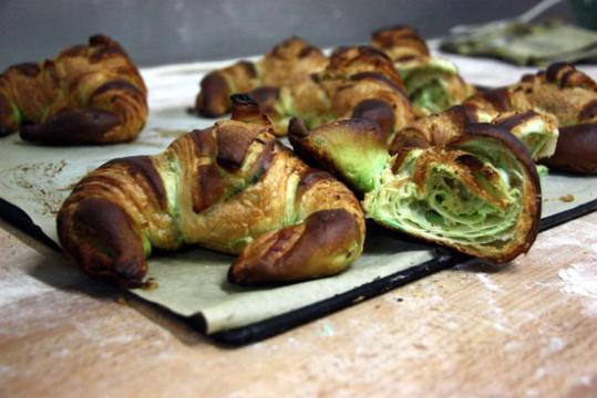 Imatge d'una safata de croissants de calçot cuits, un dels quals tallat per la meitat. ACN