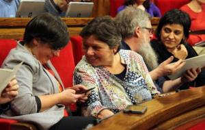 Les diputades de la CUP Mireia Boya i Anna Gabriel somriuen durant el ple del Parlament, amb Joan Garriga i Anna Gabriel al fons. ACN