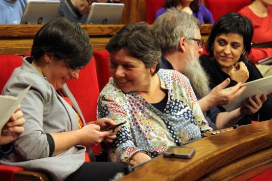 Les diputades de la CUP Mireia Boya i Anna Gabriel somriuen durant el ple del Parlament, amb Joan Garriga i Anna Gabriel al fons. ACN