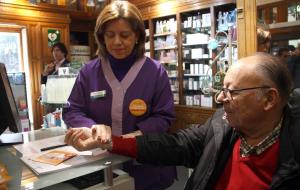 Pla detall de les mans d'una farmacèutic prenen al pols a un pacient en el marc de la campanya 'Pren-te el pols'