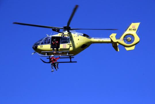 Pla detall de l'helicòpter al Pedraforca amb l'escalador rescatat a punt d'entrar-hi. ACN