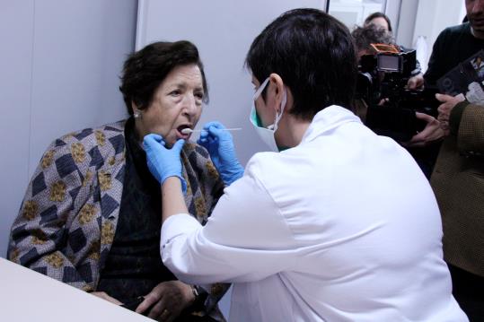 Pla general d'una infermera prenent una mostra de mucosa bucal a una familiar d'un desaparegut del Franquisme. ACN