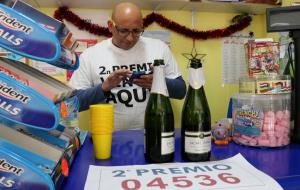 Pla mig de Ricardo Amaral, responsable de la Papereria Mimo de Calafell, i del seu sogre, amo de l'establiment, mostrant el cartell del 04536