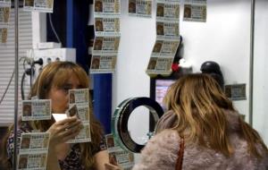 Primer pla de la treballadora d'una administració de loteria amb una clienta comprant un dècim . ACN