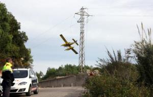 Un hidroavió passa per darrere de la torre de mitja tensió on s'ha originat l'incendi d'Albinyana