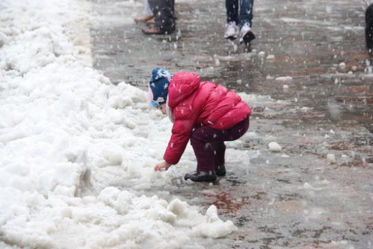 Un nen petit intenta agafar la neu que s'acumula al terra a Prades. ACN
