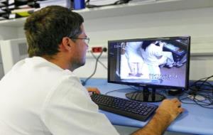 Un treballador de la Unitat d'Ictus de l'Hospital Universitari Vall d’Hebron controla un pacient ubicat al llit que té un sistema de monitoratge. Hosp