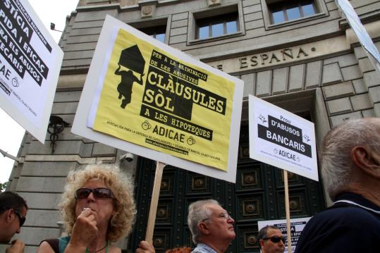 Una dona amb una pancarta en contra les clàusules sòl, davant la seu del Banc d'Espanya. ACN