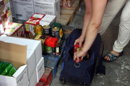 Una usuària de la Creu Roja posa els aliments a una maleta. ACN