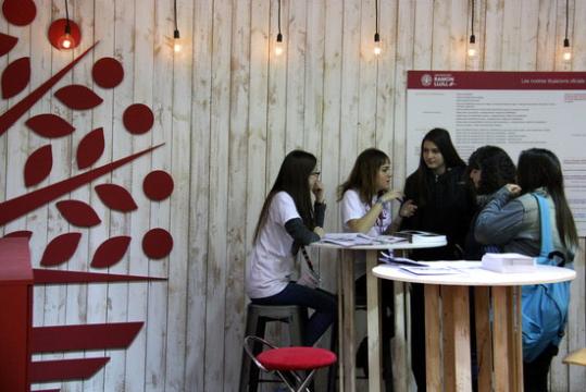 Unes estudiants de la Universitat Ramon Llull donant explicacions a alumnes d'institut a una taula. ACN