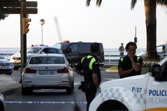 Al fons de la imatge una furgoneta funerària arribant al port de Cambrils entre un ampli cordó policial. ACN