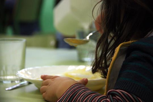 Imatge d'una nena d'esquena, menjant al menjador escolar. ACN
