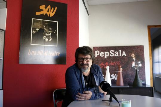 Pep Sala durant l'entrevista amb l'ACN amb un cartell al seu darrere de la gira 'Una nit al teatre' de Sau. ACN