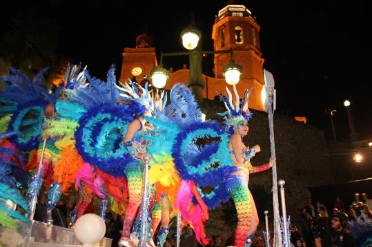 Pla general contrapicat d'una carrossa de plomes i lluentons participant a la Rua de l'Extermini, amb l'església de la Punta al fons. ACN