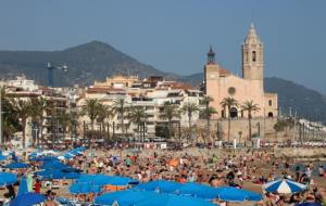 Pla general de la platja de Sitges, amb la Punta al fons, plena a vessar de gent prenent el sol durant el Divendres Sant. ACN