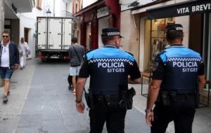 Pla mig de dos agents de la Policia Local de Sitges patrullant pel carrer Major mentre una furgoneta marxa després d'accedir-hi per equivocació. ACN
