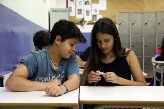 Pla mig de dos estudiants de l'Escola Pia de Diputació desmuntant una pinça d'estendre roba. ACN