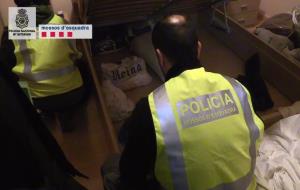 Un agent mira sota un llit en un dels registres domiciliaris en l'operació antidroga del passat 1 de febrer