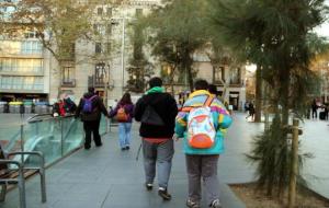 Un grup de persones amb discapacitat, acompanyades dels seus monitors, caminen agafats de la mà pel centre de Barcelona. ACN