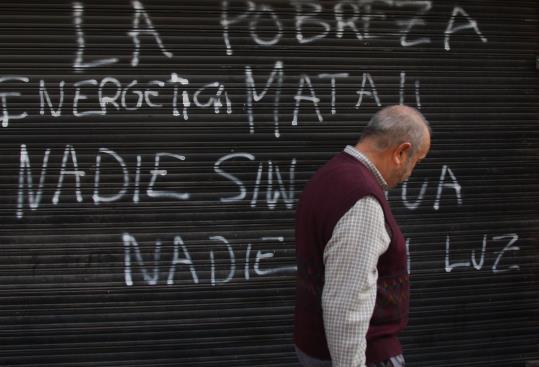 Un home passa per davant de la reixa de la seu de Gas Natural a Reus, acabada de pintar amb un grafit on s'hi llegeix 