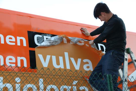 Un operari retira els vinils del bus d'Hazte Oir, on hi ha la paraula 'vulva'. Imatge del 17 de març de 2017. ACN