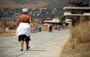Una dona passeja protegint-se del sol aquest migdia, durant la primera jornada de l'onada de calor, pel passeig marítim de Castelldefels. ACN