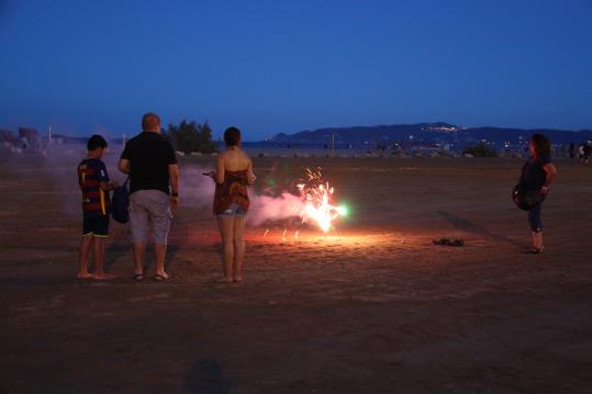 Una família davant d'un petard que han encès aquest 23 de juny del 2016 a la platja gran de l'Estartit. ACN