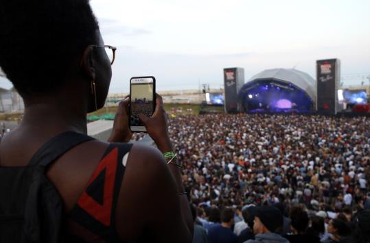 Una noia fotografia amb el seu mòbil el públic assistent al Festival Primavera Sound, davant l'escenari Ray Ban. ACN