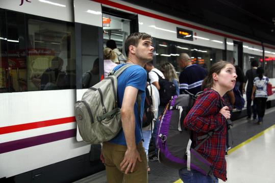 Dos usuaris consulten els horaris de Renfe i de fons es veu gent pujar al vagó. ACN