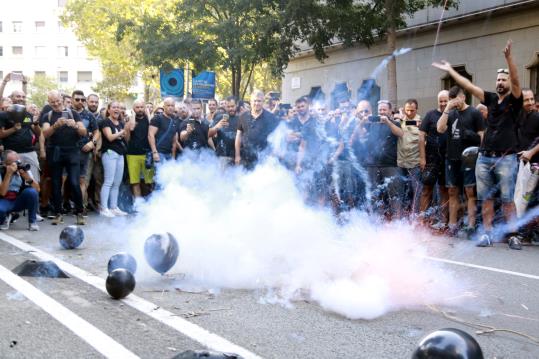 Els manifestants davant la conselleria d'Interior encenen una traca per protestar per les condicions laborals. ACN