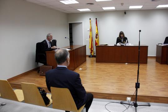 L'acusat de matar a trets a un gos a Torà, el 19 d'octubre, abans d'iniciar-se el judici, amb el seu advocat a l'esquerra i la jutgessa al fons. ACN